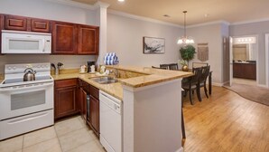 Una cocina moderna con armarios de madera, una isla central, microondas, estufa y lavavajillas.