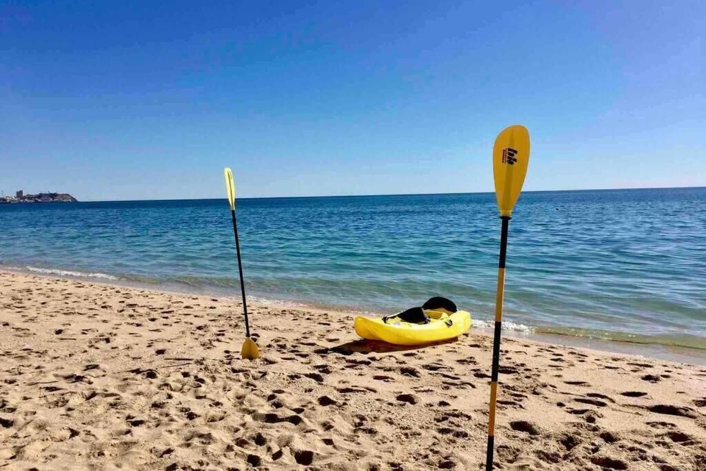 Une plage avec un kayak jaune et deux pagaies sur le sable.