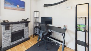 Ein moderner Arbeitsraum mit Kamin aus Stein, einem Schreibtisch mit Computer und einem Bücherregal.