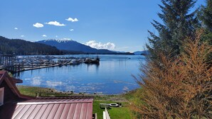 Ein Hafen mit vertäuten Booten, einem hölzernen Steg und einem Berg im Hintergrund.