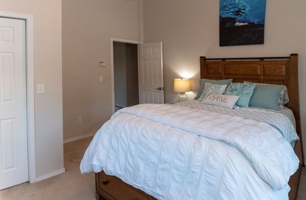 Une chambre à coucher avec un lit, une table de chevet, une lampe et un tableau au mur.