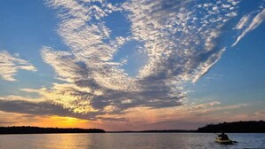 Un atardecer sobre un cuerpo de agua con un bote y una costa lejana.