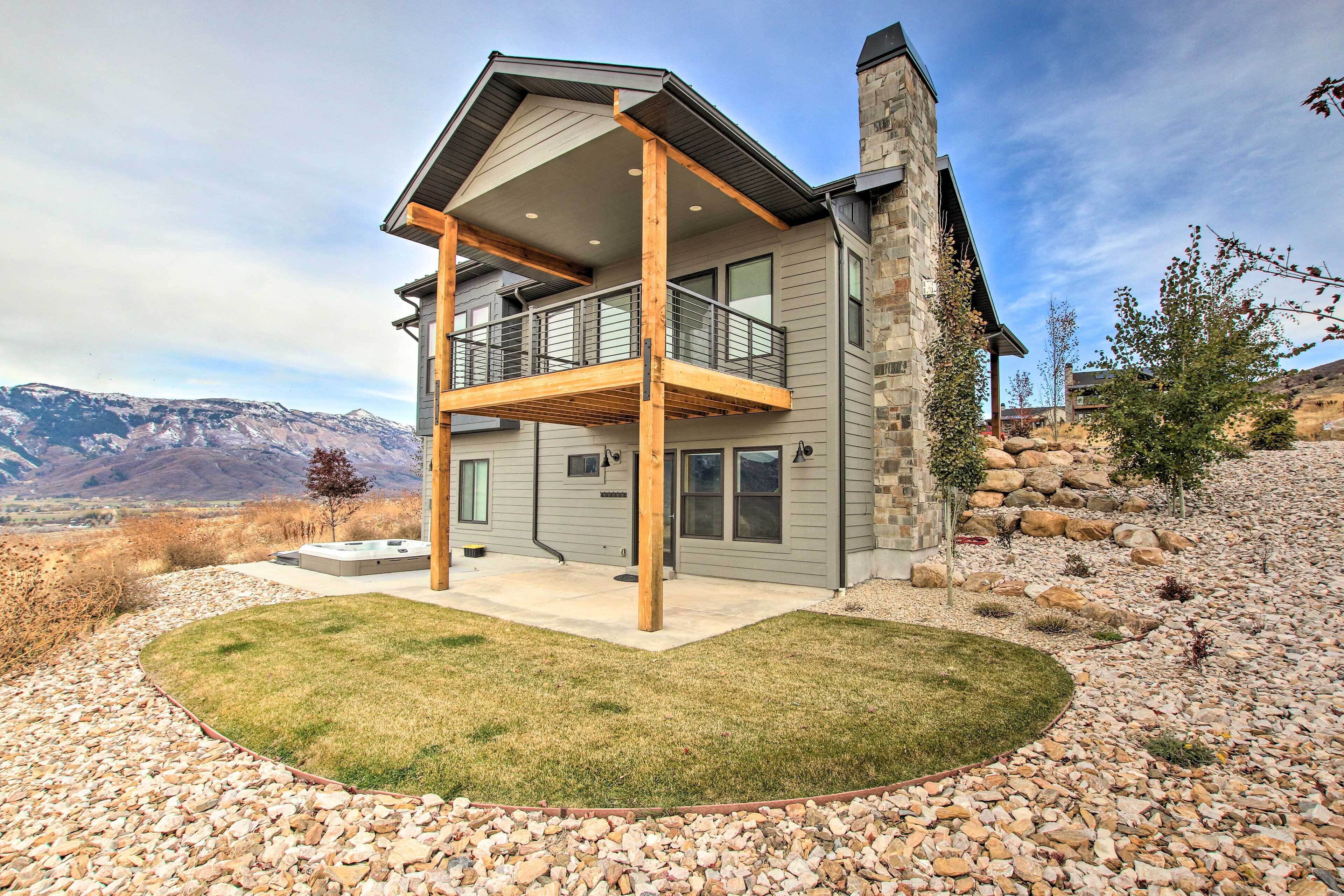 Une maison à deux étages avec un balcon, une cheminée en pierre et une vue sur les montagnes.