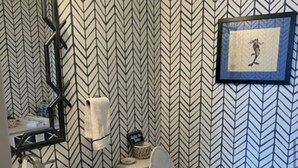A bathroom with a white sink, toilet, and mirror. The walls have a black and white chevron pattern. - Eloquently decorated 1 bedroom, 1 1/2  bath condo. Beautiful water views/balcony (West Palm Beach)