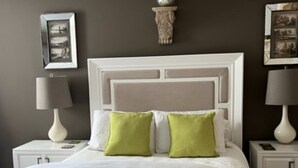 A neatly made bed with white linens and two green pillows, flanked by white nightstands with lamps. - Eloquently decorated 1 bedroom, 1 1/2  bath condo. Beautiful water views/balcony (West Palm Beach)