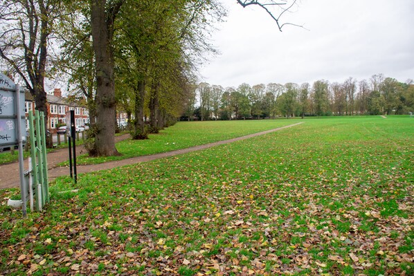 A park with a grassy field, trees, and a path.