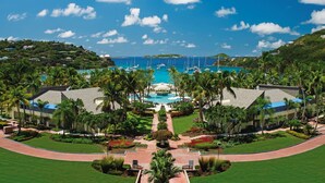 Un resort con piscina central, palmeras y vista al océano.