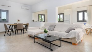 A modern living room with a sofa, coffee table, dining table, and chairs. - YourHouse Goet, villa with private pool (Sa Pobla)
