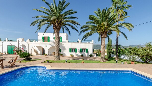 A pool with a white building in the background, palm trees, and a clear sky. - YourHouse Goet, villa with private pool (Sa Pobla)