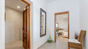 A hallway with a wooden door, a mirror, a wicker chair, and a vase. - YourHouse Goet, villa with private pool (Sa Pobla)