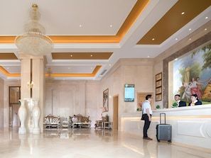 A hotel lobby with a reception desk, seating area, and a large chandelier. - Vienna International Hotel (Zhuhai)