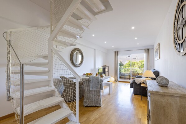 A modern interior with a white staircase, a dining area, and a view to the outside.