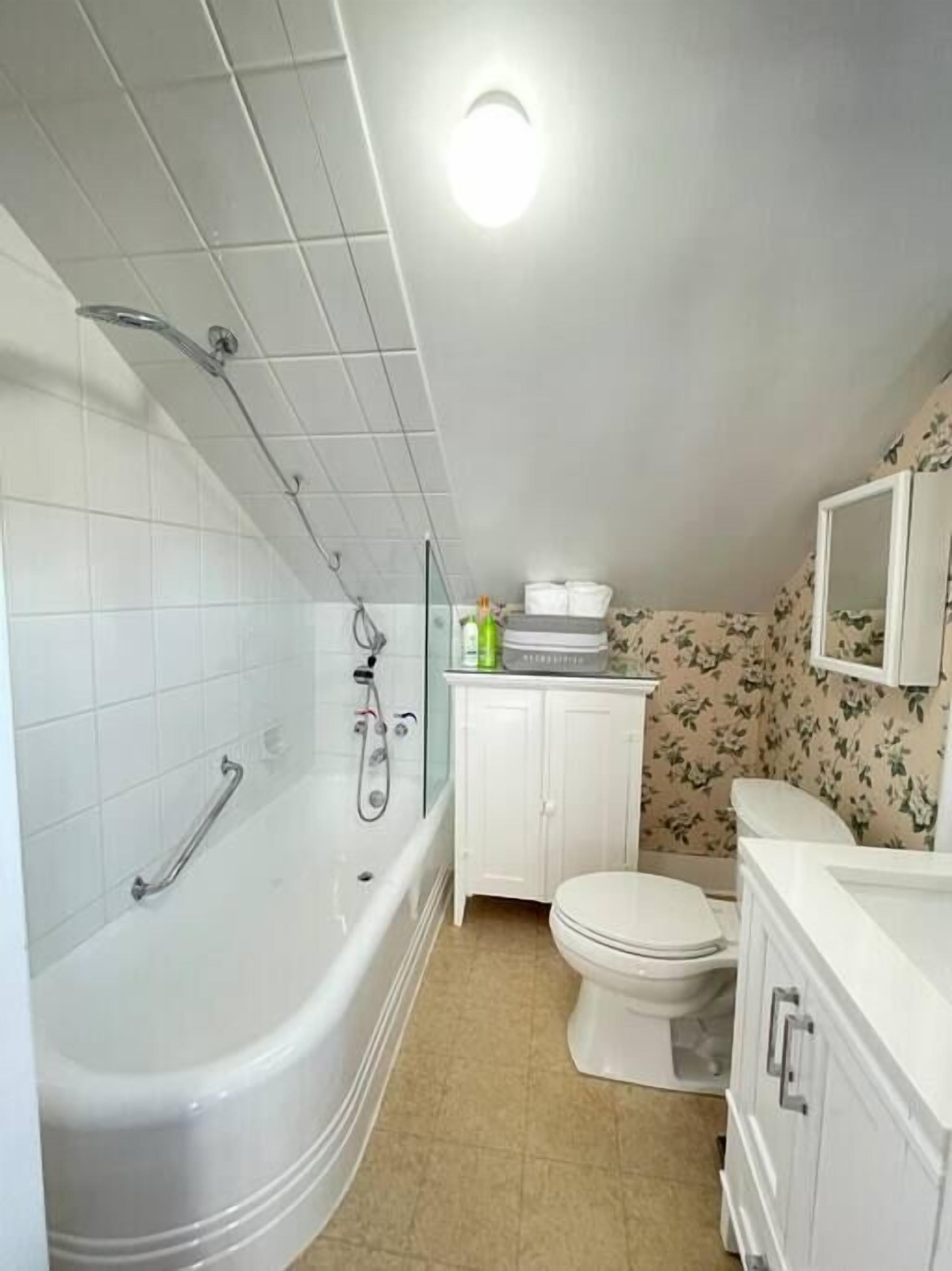 A bathroom with a white bathtub, a toilet, and a sink with a mirror above it.
