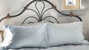 A bed with a metal headboard and two pillows.