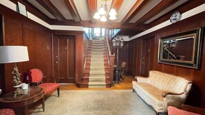 Une pièce spacieuse avec un escalier en bois, un canapé, un fauteuil et une lampe.