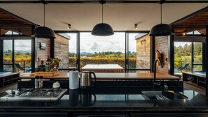 A modern kitchen with a large island, a dining area with a view, and a bar area with a view. - Boato Hotel (El Penol)