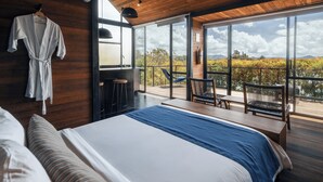 A modern bedroom with a large bed, a wooden ceiling, and a balcony with a view of the countryside. - Boato Hotel (El Penol)