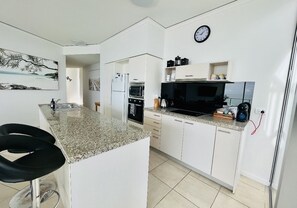 Enjoy cooking in this well-lit kitchen with a central island, white cabinetry, and stainless steel sink.