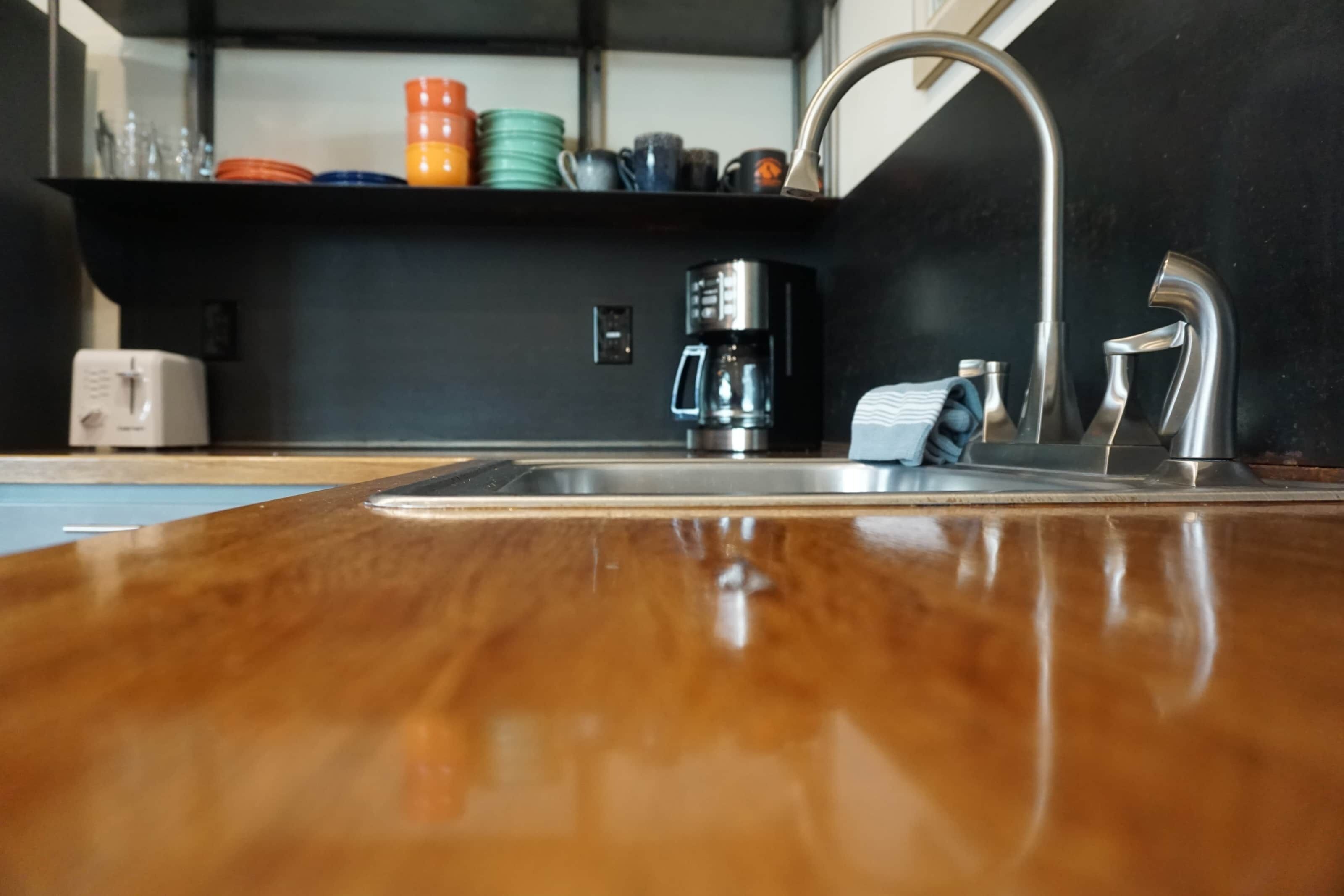 A kitchen with a stainless steel sink, a coffee maker, and a towel hanging on the faucet.