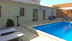 A stone building with a pool, outdoor furniture, and an air conditioning unit. - Awesome home in Lisane Tinjske (Lisane Tinjske)