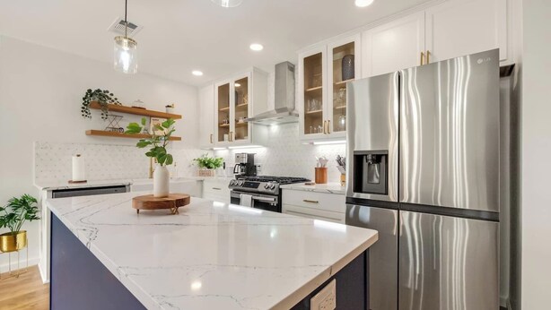 A modern kitchen with white cabinets, a stainless steel refrigerator, a built-in oven, and a marble island. - Bellini House / Modern 3BD Near Dallas (Richardson)