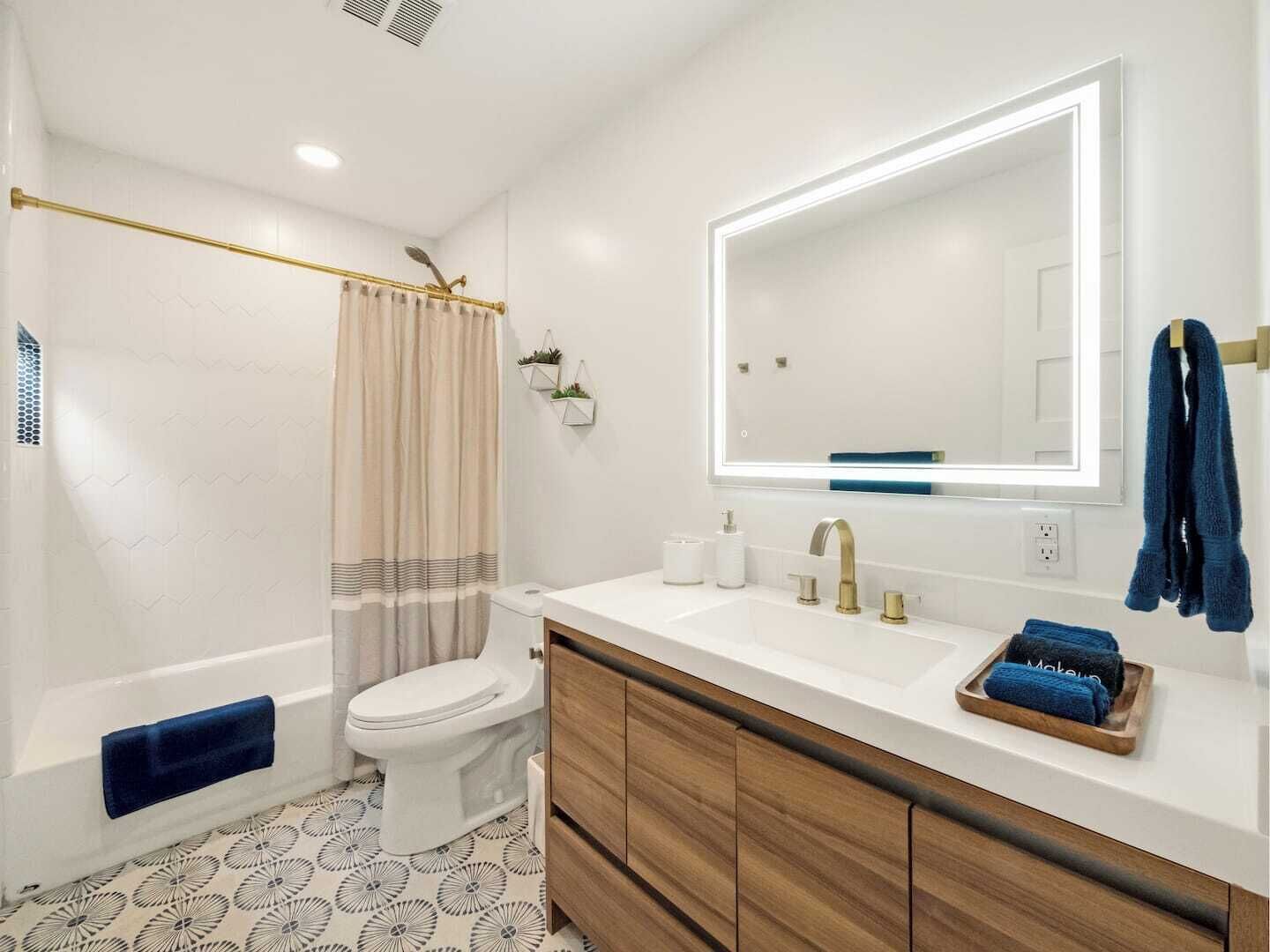 Een moderne badkamer met een badkuip, toilet, wastafel met spiegel en douchegordijn.