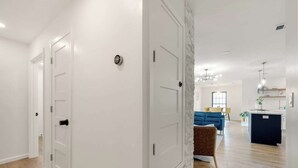 A modern interior with white walls, a wooden floor, and a kitchen area with a blue sofa and a brown chair. - Bellini House / Modern 3BD Near Dallas (Richardson)