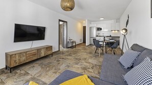 A modern living room with a flat-screen TV, a wooden cabinet, a grey sofa with patterned cushions, and a stone-tiled floor. - wema alto (Playa Blanca)
