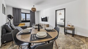 A modern hotel room with a dining area, a sofa, a TV, and a bed. - wema alto (Playa Blanca)