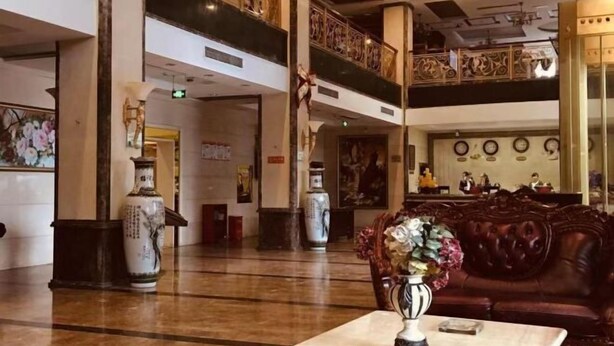 A lobby with a marble floor, a brown leather sofa, and two large vases on a table. - Ru Jiang Hotel (Zhong County)