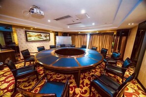 A conference room with a round table, chairs, a projector, and a large screen. - Ru Jiang Hotel (Zhong County)