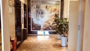 A hallway with a marble floor, a large painting of a waterfall, and potted plants. - Ru Jiang Hotel (Zhong County)