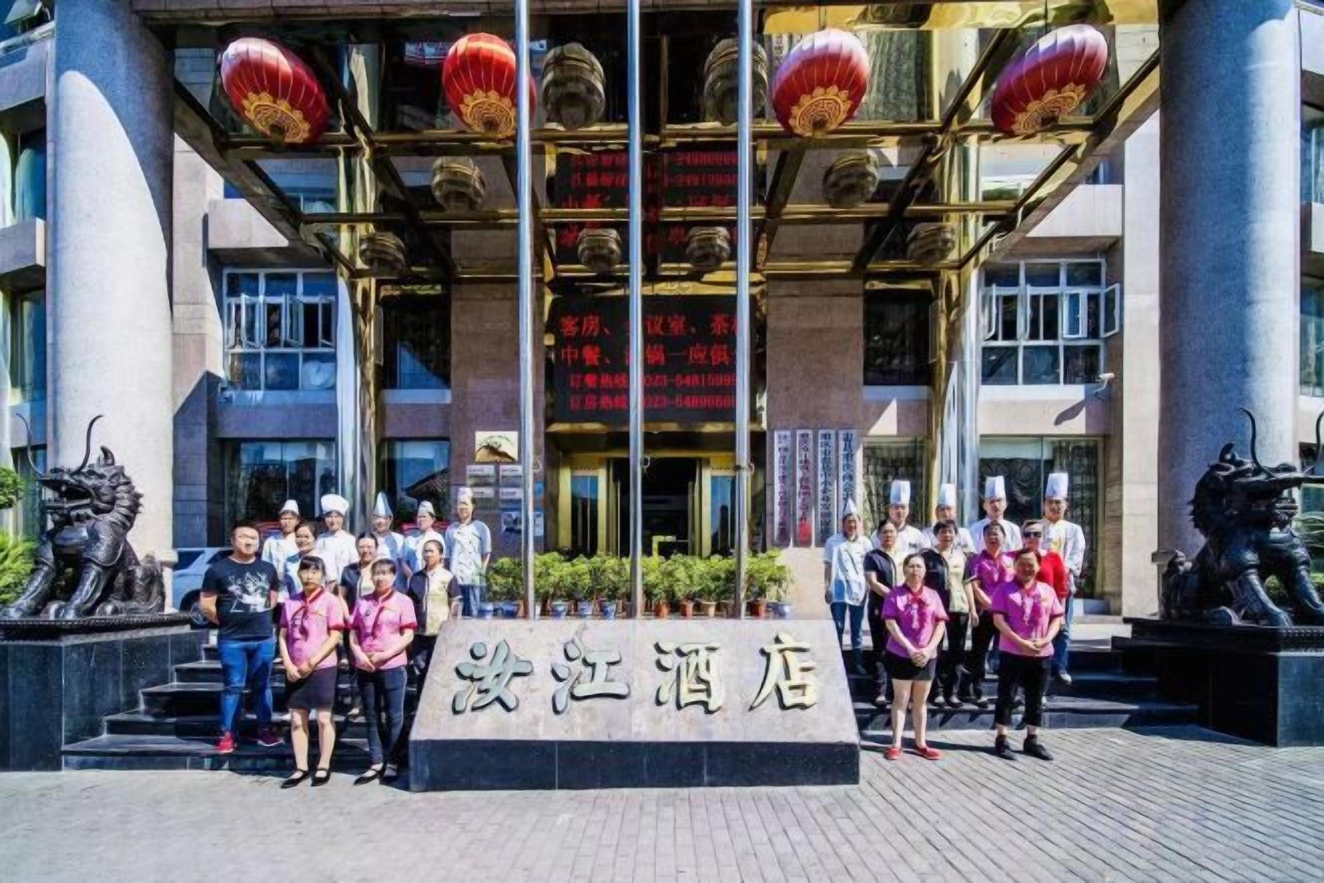 A group of people standing in front of a building with a sign that reads 'Shenzhen Hotel'.