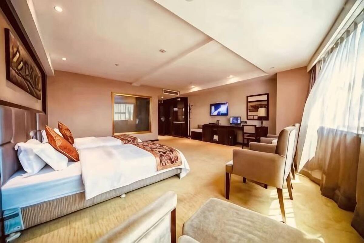 A hotel room with a bed, a desk, a chair, a television, and a large window.