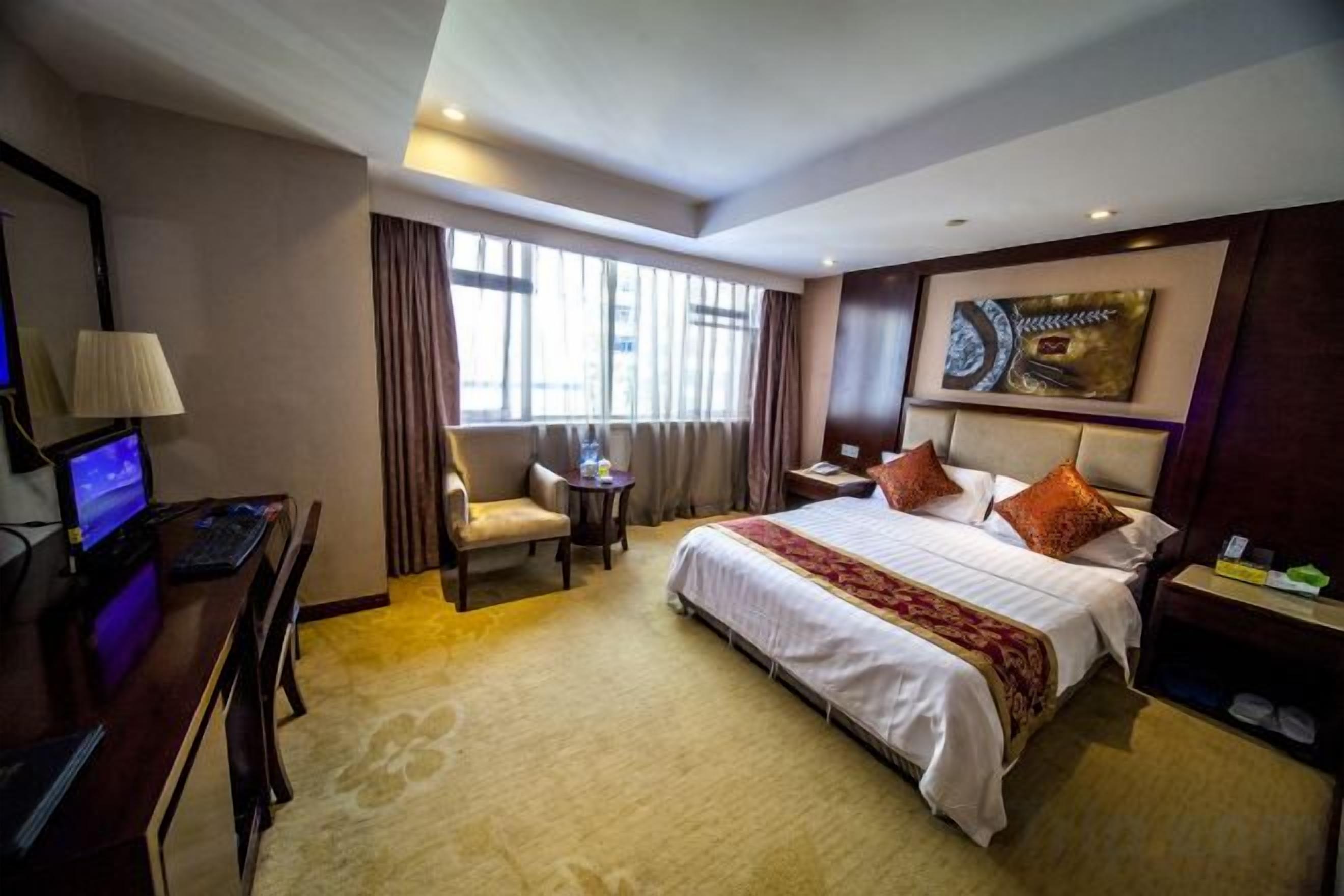 A hotel room with a bed, desk, chair, and a small table.