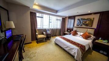 A hotel room with a bed, desk, chair, and a small table.