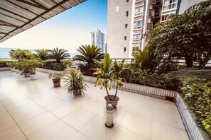 A rooftop terrace with potted plants and a view of the city. - Ru Jiang Hotel (Zhong County)