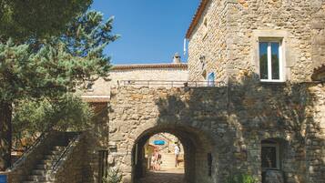 A stone building with an archway entrance, a staircase, and a small window.