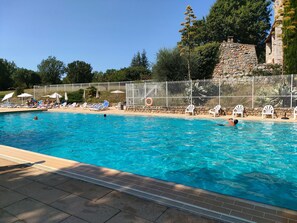 A swimming pool with clear blue water, surrounded by lounge chairs and umbrellas. - Appartement Confortable au Calme | Parking Gratuit (Casteljau)