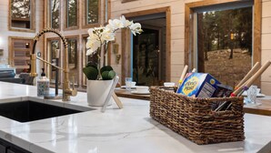 Un comptoir de cuisine avec un évier en marbre, un vase rempli de fleurs blanches, un panier en osier contenant des ustensiles et une boîte de biscuits Honey Maid.