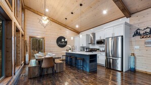 Une cuisine moderne avec des meubles en bois, un réfrigérateur en acier inoxydable et un îlot central doté de tabourets de bar.