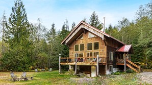 Une cabane en bois dotée d’une terrasse, entourée d’arbres.