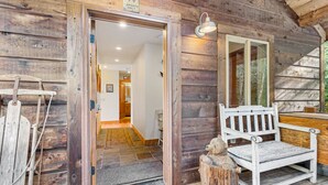 L’entrée d’un chalet en bois, avec un banc et un panneau d’avertissement.