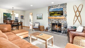A spacious living room with a stone fireplace, comfortable seating, and a dining area in the background. - Valley View- best view, private acreage, ping pong (Gold Bar)