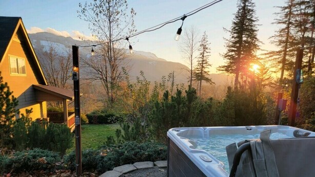A hot tub in a garden with a house and mountains in the background. - Valley View- best view, private acreage, ping pong (Gold Bar)