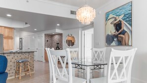 A modern kitchen with white cabinets, a dining area with white chairs, and a chandelier. - Nautical Two Bedroom Condo Overlooking the Perdido Bay and Pools! Complimentary Boat Slip! (Orange Beach)
