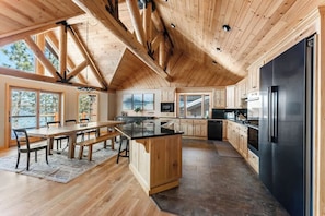 A modern kitchen with wooden beams, a large island, and a black refrigerator.