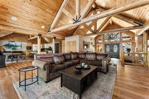 A spacious living area with a large sectional sofa, a coffee table, and a wooden ceiling with exposed beams.