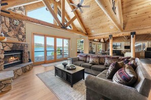 A spacious living room with a stone fireplace, a large sofa, and a view of the outdoors.