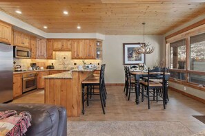 A kitchen with wooden cabinets, a central island, and a dining area with chairs and a table.